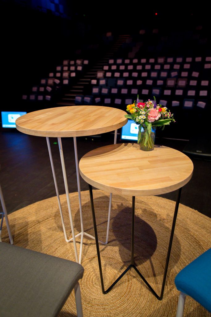 mobilier sur scène, mange-debout, tapis en jute rond et bouquet de fleurs, agence Parade