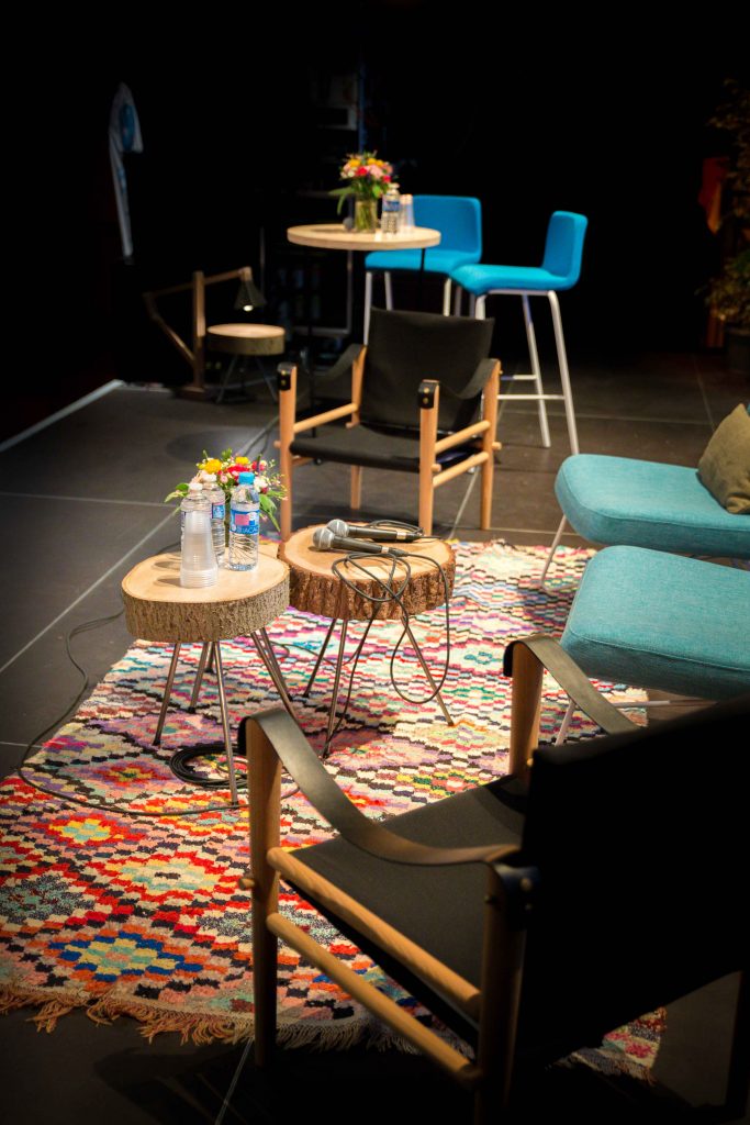 mobilier sur scène : tapis boucherouite, tables en rondins de bois, fauteuils et mange-debout, agence Parade