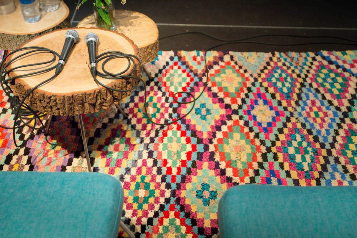 tapis boucherouite motifs roses, fauteuils en tissu bleu tables en rodin de bois et micros, agence Parade