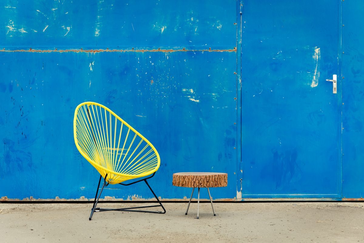fauteuil Acapulco jaune, de la marque Boqa, table basse en rodin de bois, portail bleu industriel, agence Parade